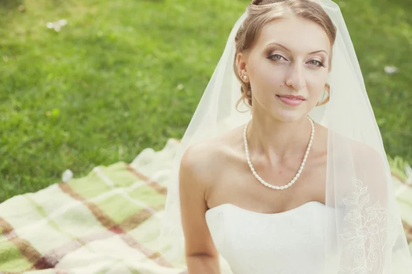 Mariée avec bouquet assis dans le parc — Photo