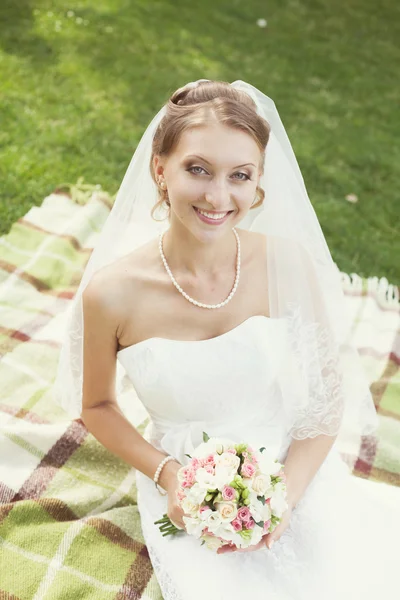 Sposa con bouquet seduta nel parco — Foto Stock