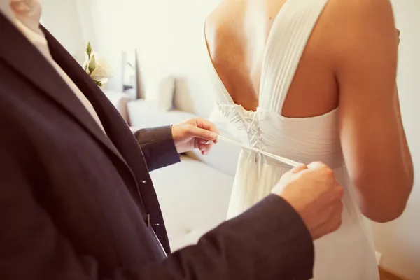 Ženich, pomáhat nosit svatební šaty — Stock fotografie