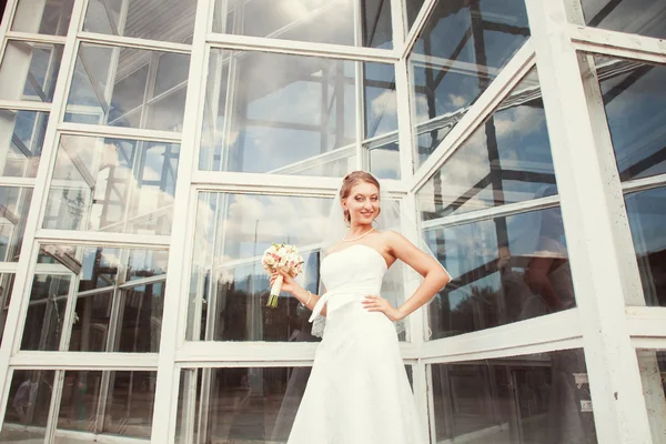 Novia con ramo cerca del edificio de vidrio — Foto de Stock