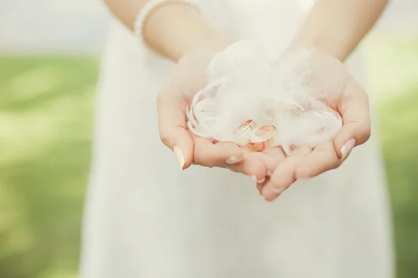 Anillos de boda y plumas en las manos — Foto de Stock