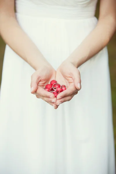 Anéis de casamento e cereja nas mãos da noiva — Fotografia de Stock