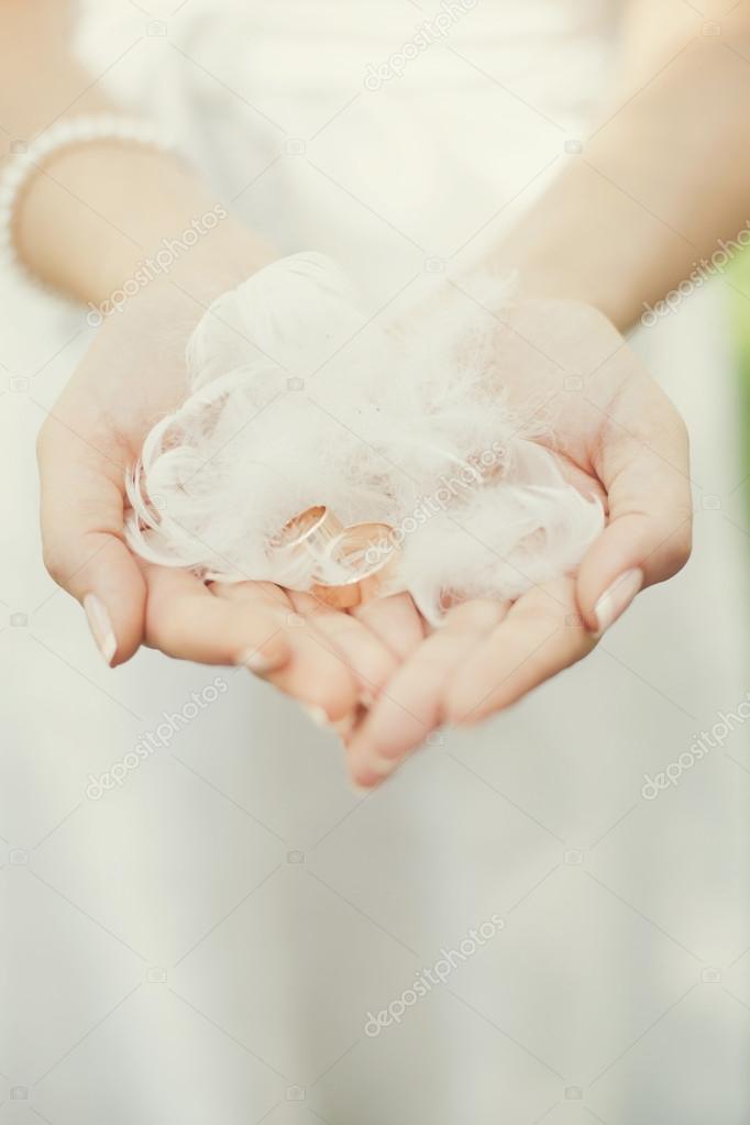 Wedding rings and feathers in the hands