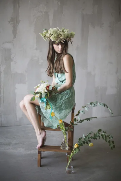 Beautiful girl, brunette with a bouquet of flowers and a wreath — Stock Photo, Image