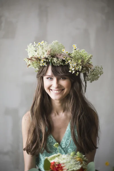 Beautiful girl, brunette with a bouquet of flowers and a wreath — Stock Photo, Image