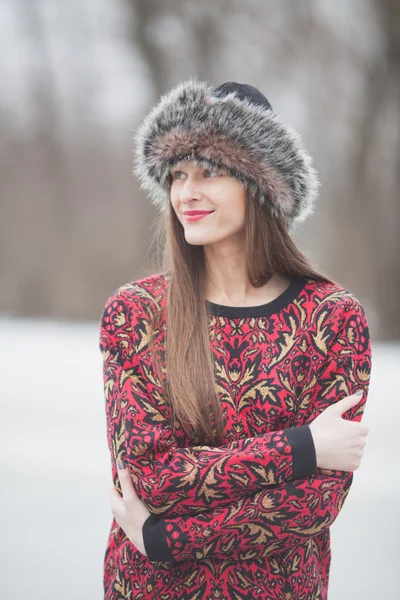 Vacker flicka i parken i vinter, i en pälsmössa — Stockfoto