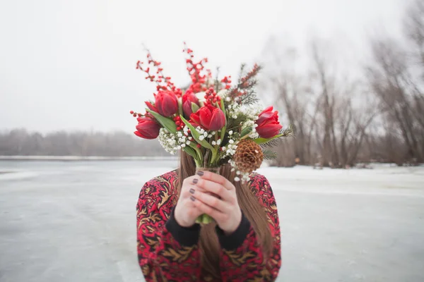 Gyönyörű lány a parkban, télen, egy-egy csokor piros flo — Stock Fotó