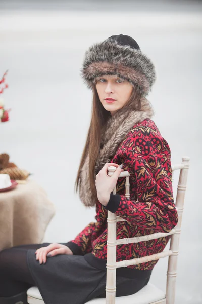 Vacker flicka i parken i vinter, i en pälsmössa på en romantisk — Stockfoto