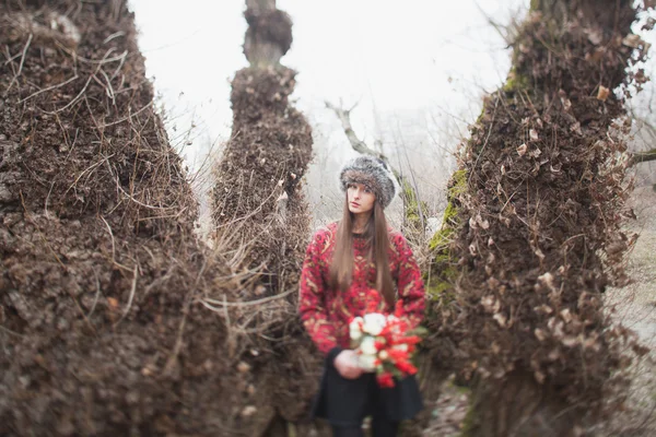 Menina bonita no parque no inverno, em um chapéu de pele com um buque — Fotografia de Stock