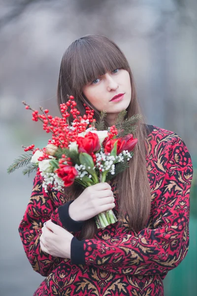 Hermosa chica en el parque en invierno, con un ramo de flo rojo — Foto de Stock