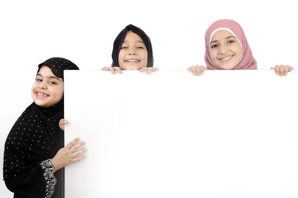 Tres colegialas sosteniendo una señal blanca en blanco para su mensaje. — Foto de Stock