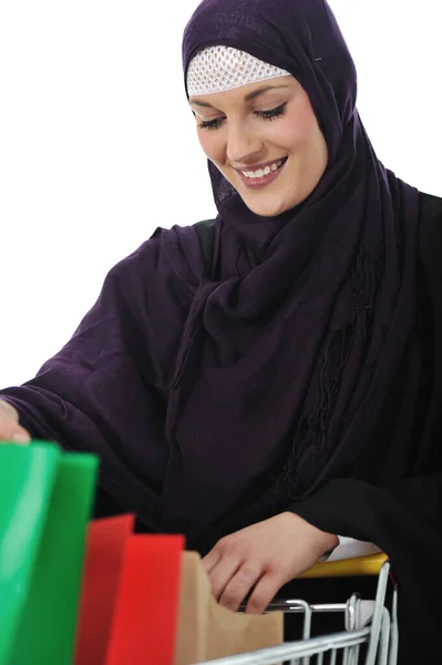Felice donna musulmana con carrello della spesa su bianco — Foto Stock