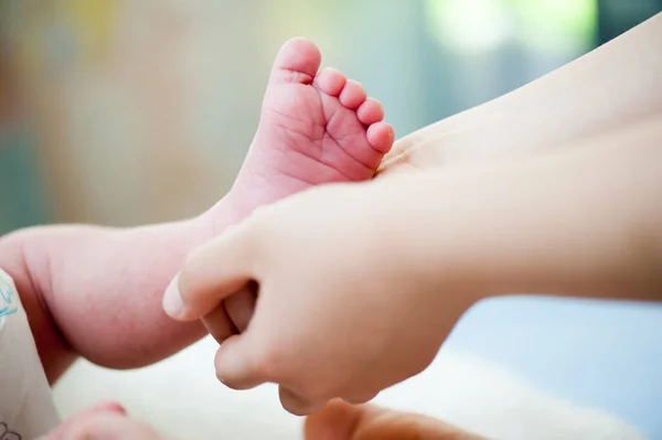 Los pies de un bebé recién nacido. Familia feliz, mamá y papá abrazan sus piernas de bebé. — Foto de Stock