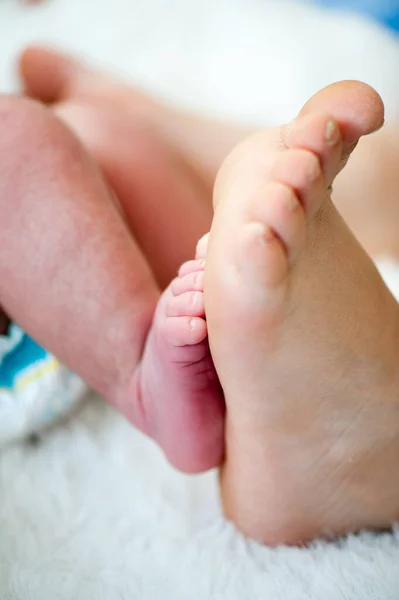 Pés de um recém-nascido. Família feliz, mamãe e papai abraçam suas pernas de bebês. — Fotografia de Stock