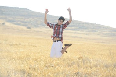 Genç adam sarı çayırda zıplıyor