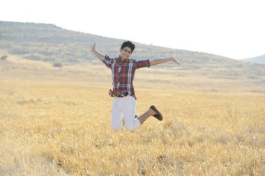 Genç adam sarı çayırda zıplıyor