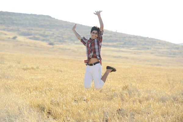 Genç adam sarı çayırda zıplıyor