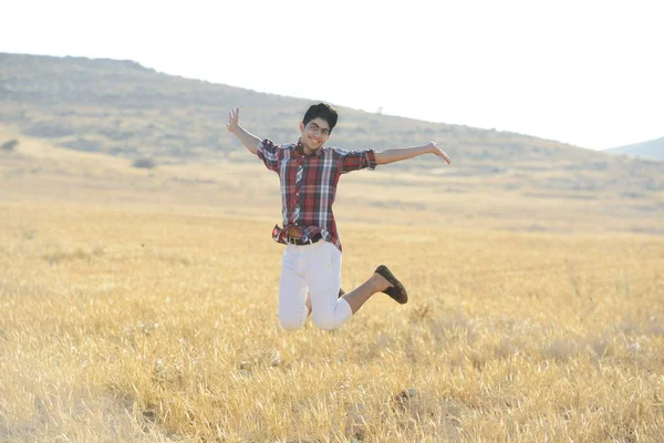 Genç adam sarı çayırda zıplıyor