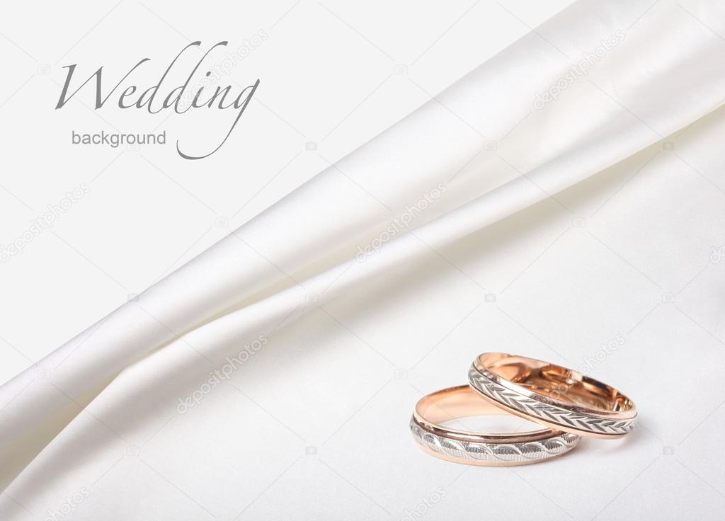 Wedding rings on white silk background