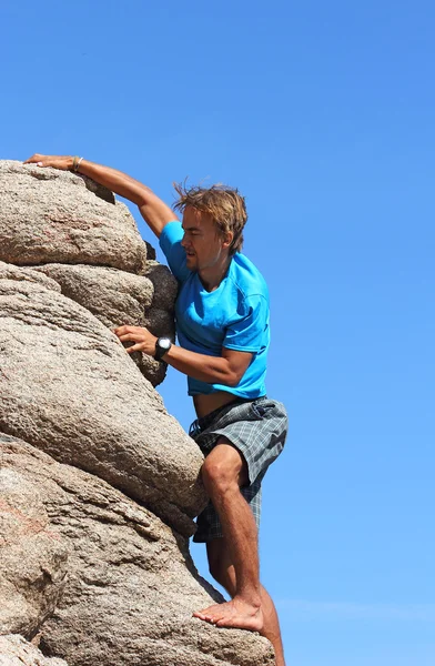 Ung man klättrar på en sten — Stockfoto