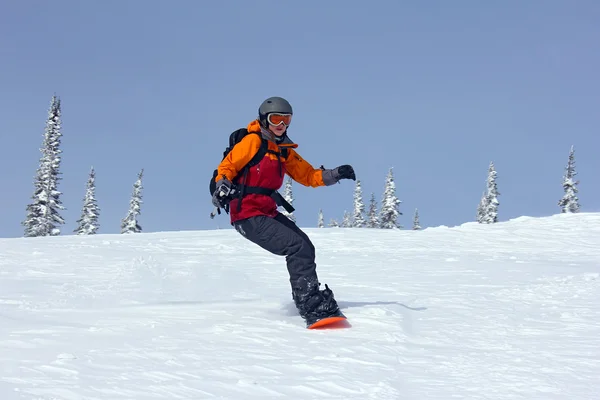 Dziewczyna pędzi w dół stoku na desce snowboardowej — Zdjęcie stockowe