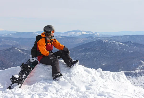 Flicka med snowboard på toppen av berget Stockbild
