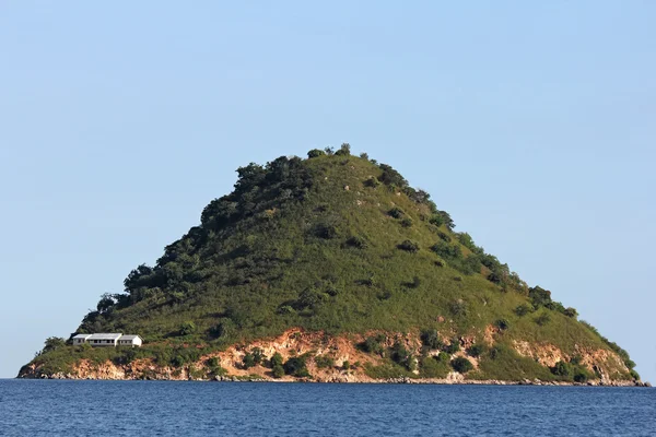 Uma ilha piramidal solitária no mar com casa branca — Fotografia de Stock