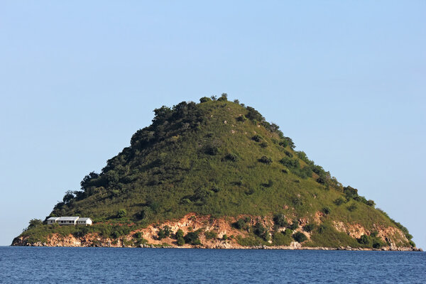 a lonely pyramidal island in the sea with white house