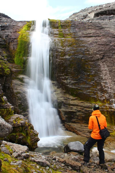 Girl standing near the beautiful waterfall and and looking at it — Stock Photo, Image