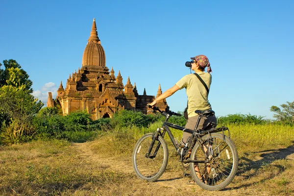 Flicka fotograf på en cykel tar en bild av templet i Royaltyfria Stockfoton
