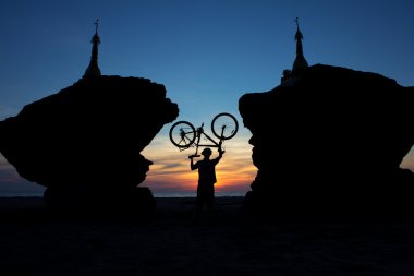 silhouette of a cyclist between two stupas on the background of clipart