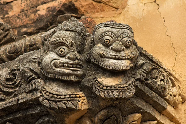 Statue of two faces(full face) on the corner of ancient temple — Stock Photo, Image