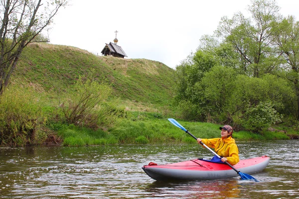 Ragazza in kayak sul fiume e una chiesa di legno sulle rive — Foto Stock