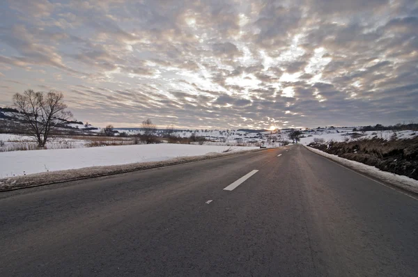 Дорога зимой с солнцем на закате — стоковое фото