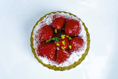 Çilekli mini tart pudra şekerli, narin hamur işi, beyaz tabakta izole edilmiş.