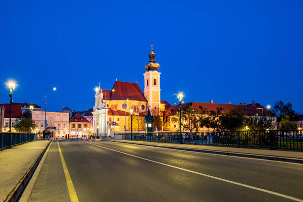 Gyor, city in Hungary, baroque Carmelite church by night from bridge over Raba river