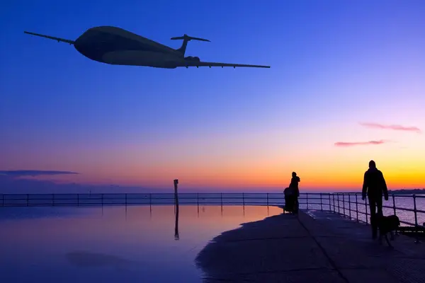 Avión volando sobre el mar y aterrizando al atardecer — Foto de Stock