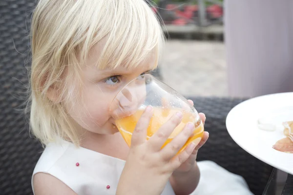 Joven chica beber jugo de naranja fuera en el jardín —  Fotos de Stock