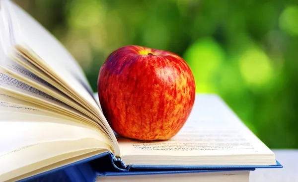 Apfel am offenen Buch — Stockfoto