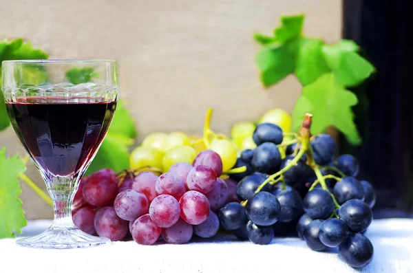 Bicchiere di vino rosso con chicchi d'uva su un tavolo — Foto Stock