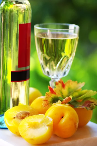 White wine bottle, glass and plums — Stock Photo, Image