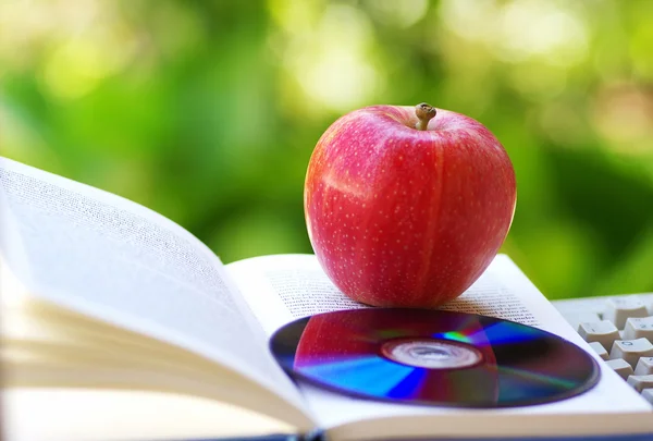 Manzana madura, dvd y libro abierto —  Fotos de Stock