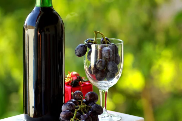 Decorated bottle of red wine with Christmas presents. — Stock Photo, Image