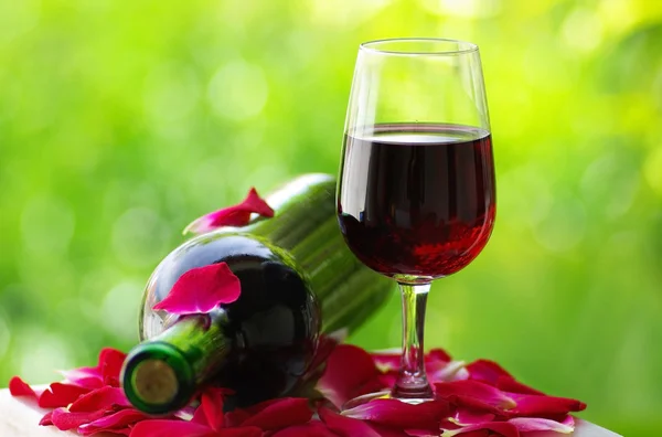 Pétales de rose dans un verre de vin rouge . — Photo