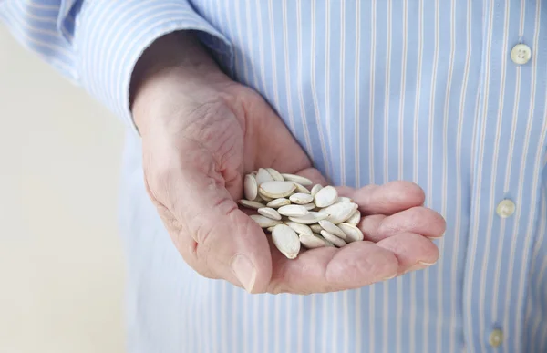 Homem segurando sementes de abóbora na mão — Fotografia de Stock
