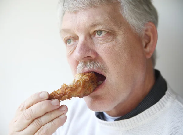 Starší člověk jíst smažené kuřecí stehno — Stock fotografie