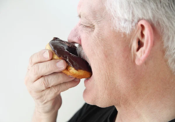 Homem leva mordida de donut — Fotografia de Stock