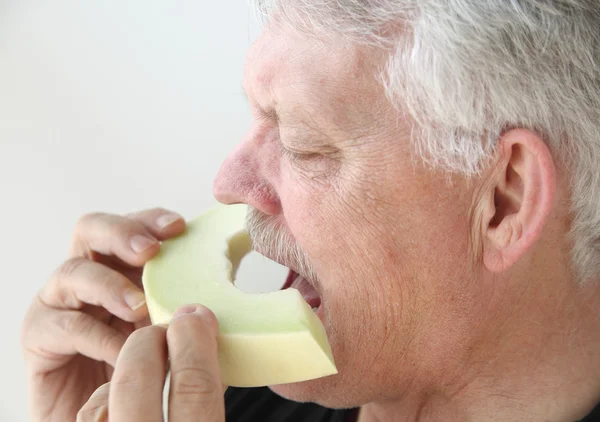 Man bites into slice of honeydew melon — Stock Photo, Image