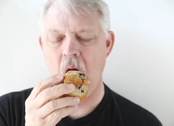Homem mais velho com muffin de mirtilo — Fotografia de Stock