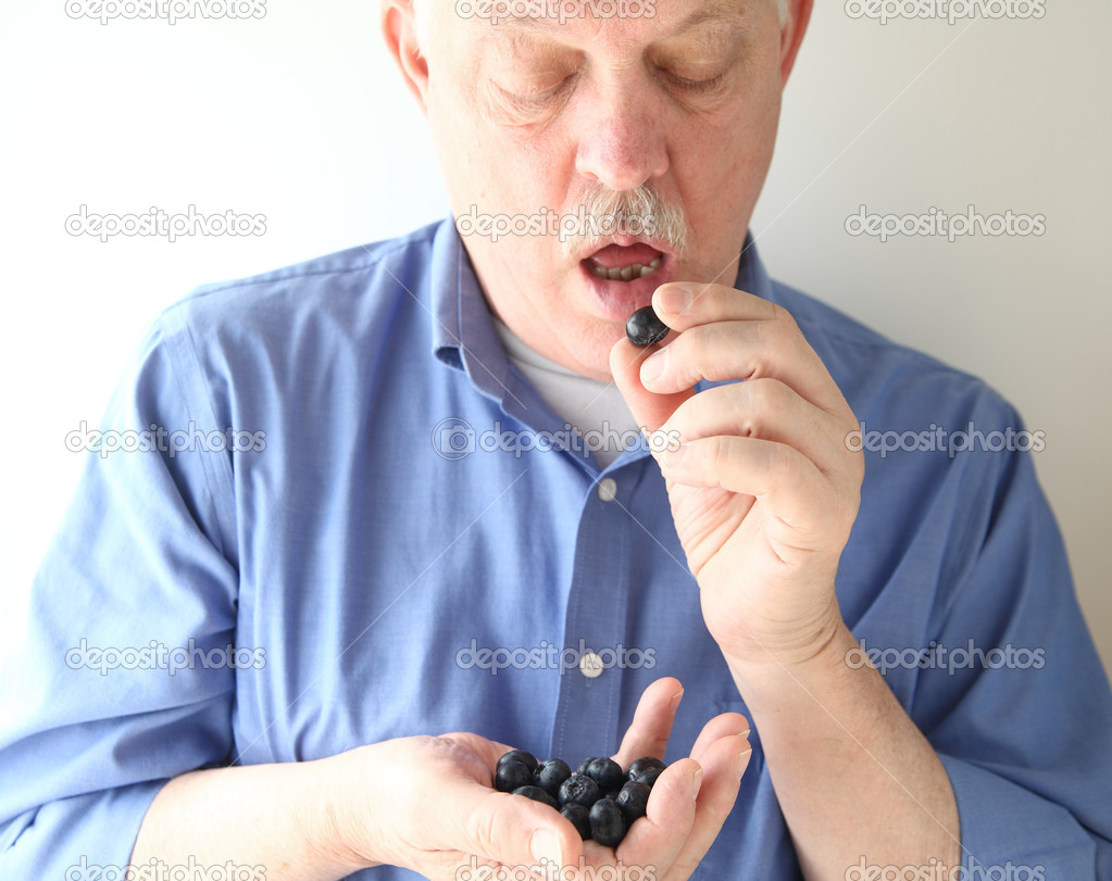 senior man eating blueberries